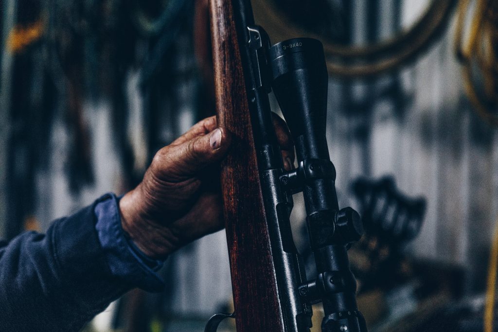 a person holding a rifle with scope